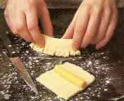 Place a 3-inch roll of marzipan across the middle of a dough square. Fray the edge by making cuts at least every quarter inch.