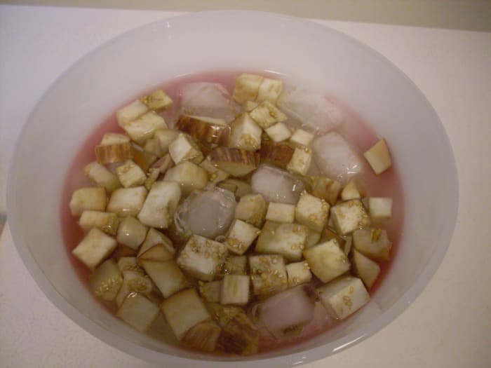 lägg omedelbart auberginebitarna i iskallt vatten (kallat "chockerande") för att stoppa tillagningen. Jag brukar använda en skål med vatten, men en skål fungerar också.