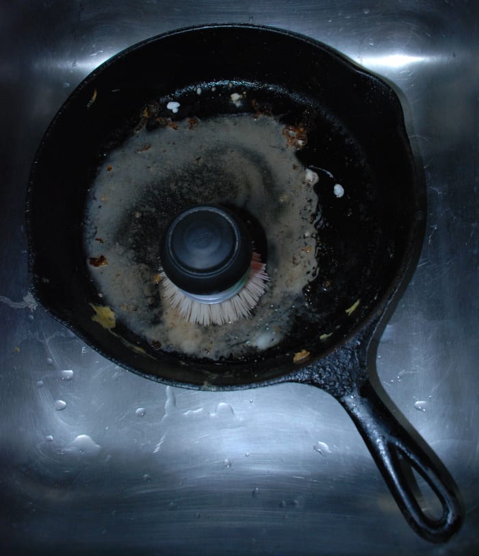 Scrubbing the baking soda-water mixture into the pan with a strong brush will help break down burnt food and other residue.