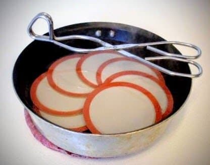 Set lids in a small pan and pour scalding water over them, or simmer them slowly in a saucepan of water. DO NOT BOIL! Leave them in the water until you use them, so they remain warm with softened rubber rings.
