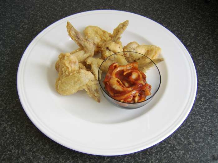 The spiced onions are added to a small dish and plated with the deep fried chicken wings clustered around it