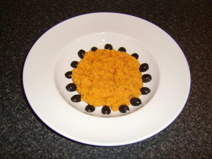 The sweet potato is piled in the centre of the plate and surrounded by the pitted and halved black olives