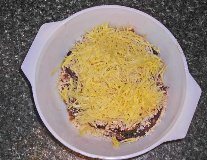 Stuffed eggplant sprinkled with breadcrumbs and grated cheese, ready to be baked for 20 minutes.
