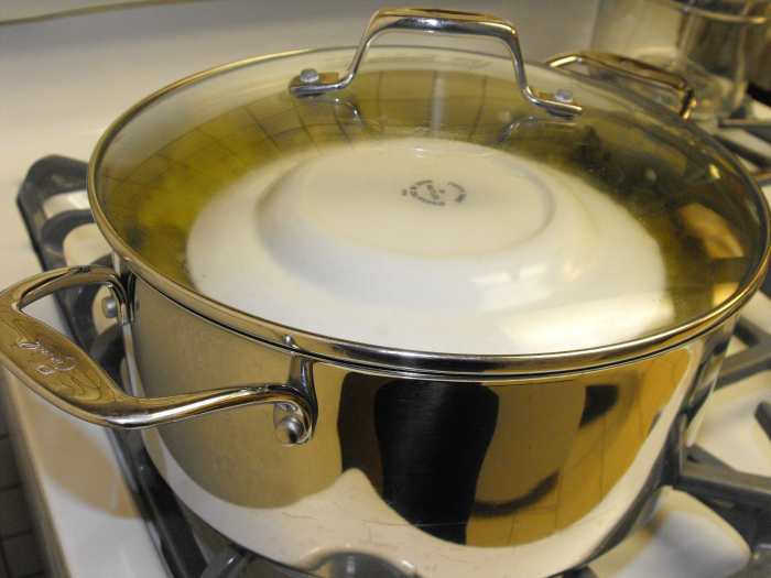 In this final photo, I show the sarma ready to cook on the stove top. Covered first with a couple layers of leaves and then with an inverted plate (to keep the leaves from floating), you add water (just one layer less than the top layer of sarma).