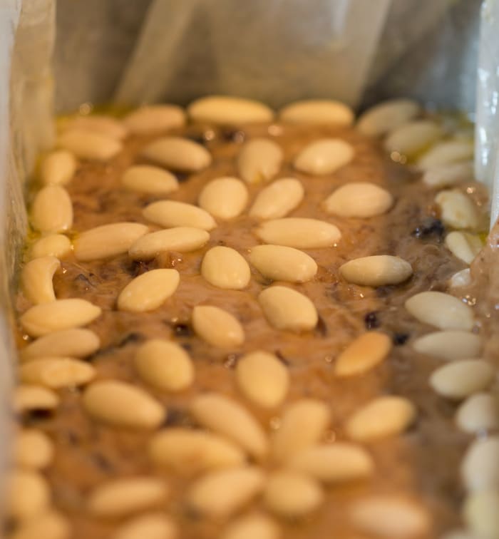 Blanched almonds atop an uncooked fruitcake in a loaf tin (my preferred tin type for baking fruitcakes)