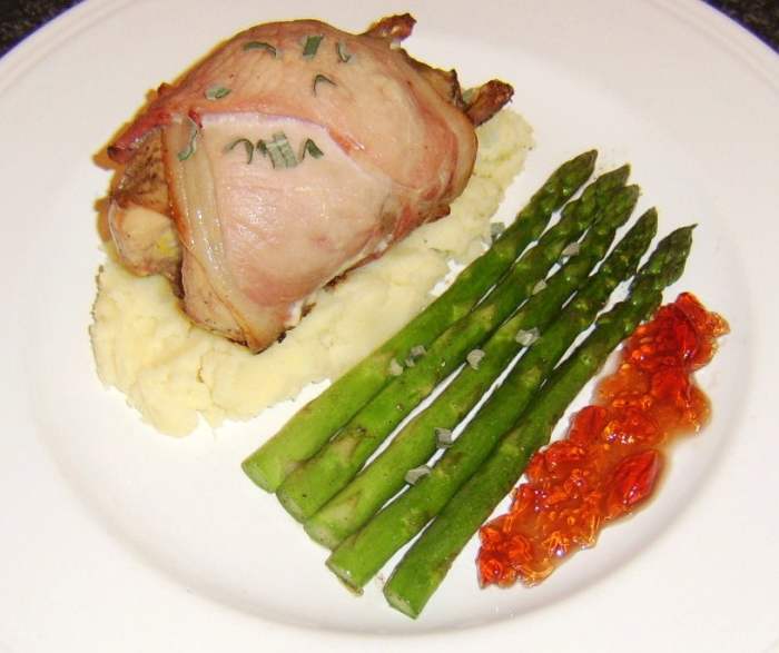 Whole partridge wrapped in bacon and roasted is served on a bed of Dijon mustard mash, with sauteed asparagus and redcurrant sauce