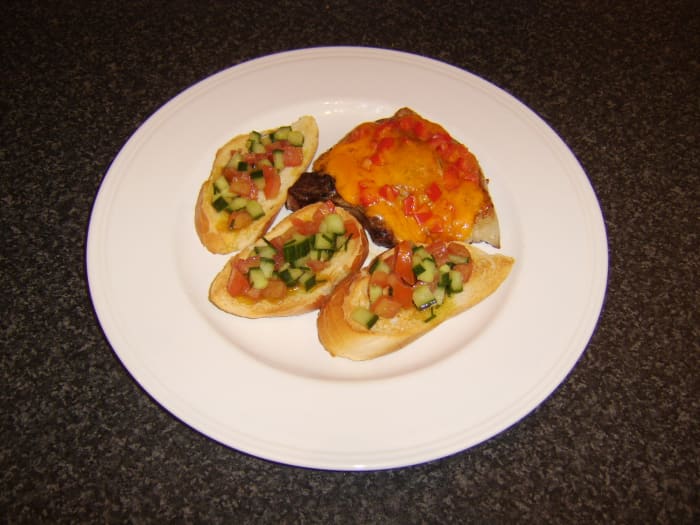 Cheese and chopped red bell pepper are melted over a pork chop which is then served with salsa based bruschetta
