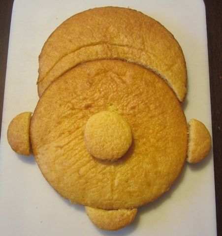 One round cake will be the main face, while the other will be cut to form the hat. The cupcakes will form the nose, ears, and chin.