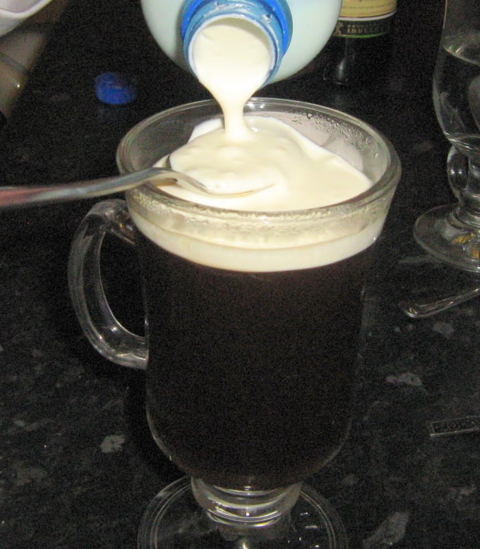 Slowly pour the cream onto the slightly angled spoon. Let the cream fall off the spoon into the glass and it will not sink.