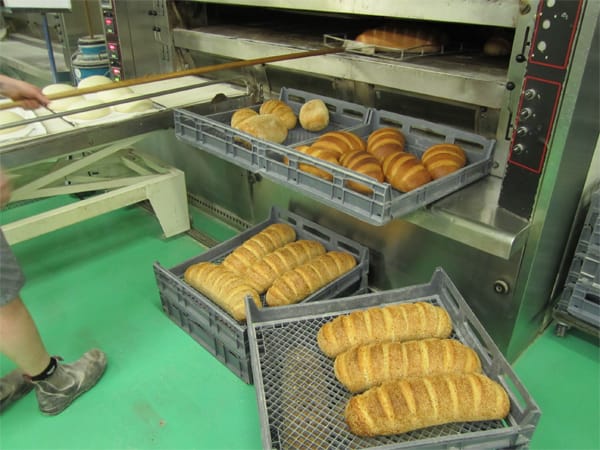 Freshly baked loaves are transferred directly onto delivery trays. Notice the next batch of loaves lined up behind ready to go in.