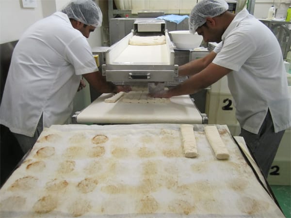 Portions of croissant dough that have been hand-portioned from the dough that has been rolled out by the machine.