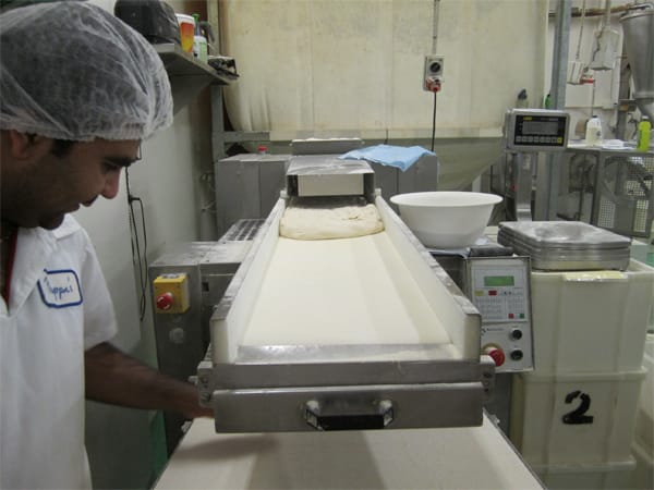 Croissant dough is rolled out on a special machine. The bakers hand-cut them into portions at the end.