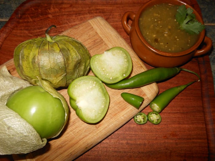 Tomatillos have a slightly sticky texture and have a thick center with seeds. They are pictured here with sliced serrano peppers.