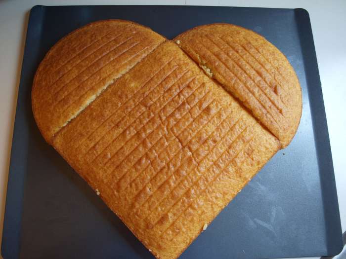 Using a large tray, assemble the unfrosted cake. Place the square cake on the diagonal and place the two halves of the circular cake at the top left and right. The heart shape is formed.