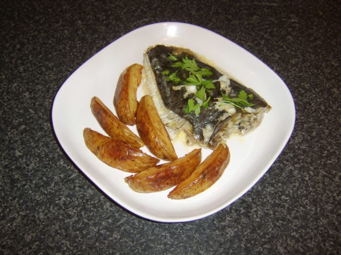 A whole, prepared flounder is baked with some subtle flavourings before being served wimply with deep fried potato wedges