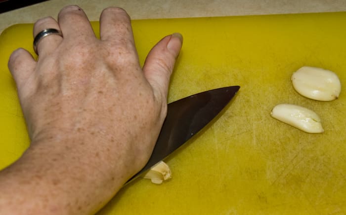 The easiest way to get the skin off the cloves of garlic is to smack it with the flat side of the knife-photo by AMB