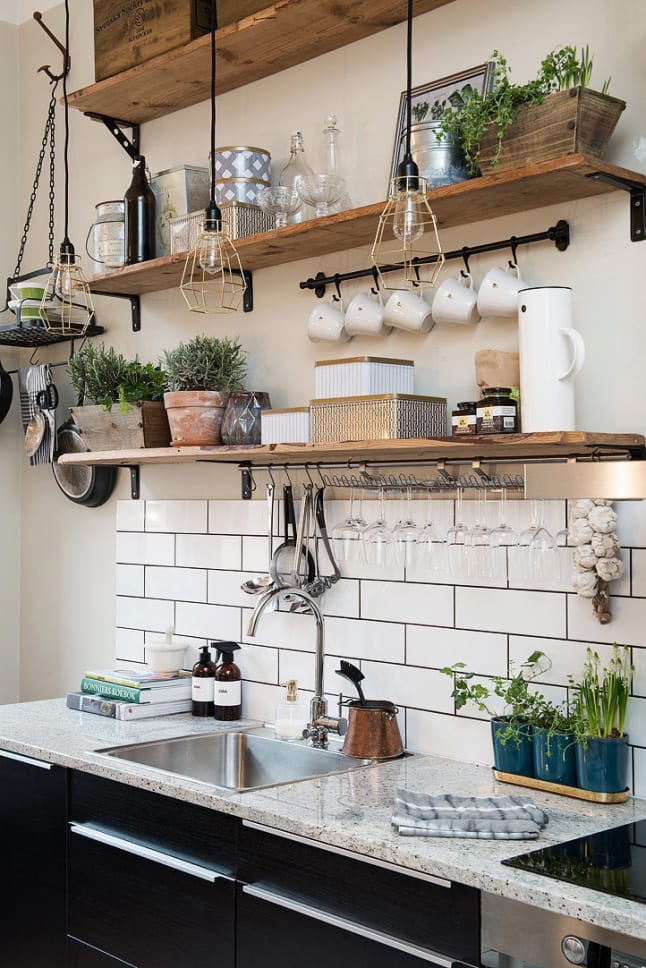 This small kitchen makes nice use of a mix of open shelves, hooks, and hanging baskets to organize kitchen items without feeling cluttered.