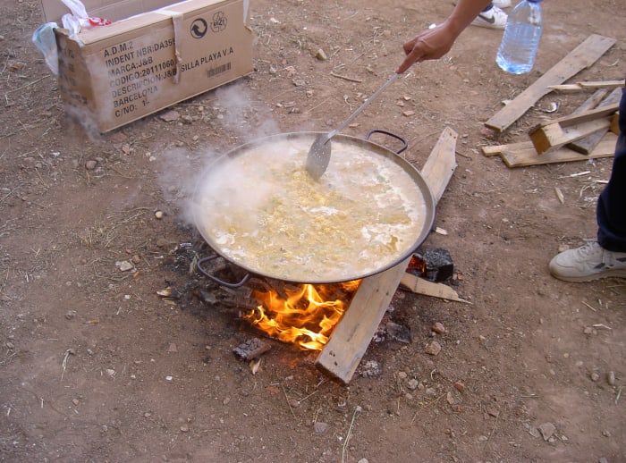 A paella pan over an open flame