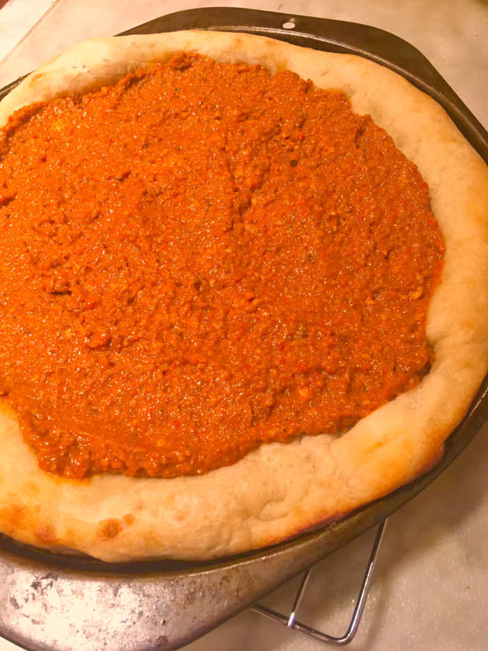 Homemade romesco sauce on a par-baked pizza crust