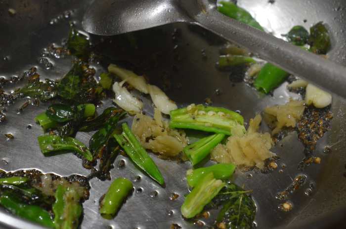 Step eight: Saute mustard seeds and curry leaves in oil. Let mustard crackle. Add chopped green chilies, hing powder, crushed ginger, and crushed garlic. Saute for a minute. Add boiled mung beans mix.