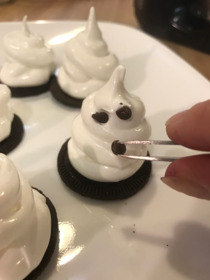 If you're as uncoordinated as I am, tweezers make placing mini chocolate chips easy! Place the chips immediately, before the ghosts set.