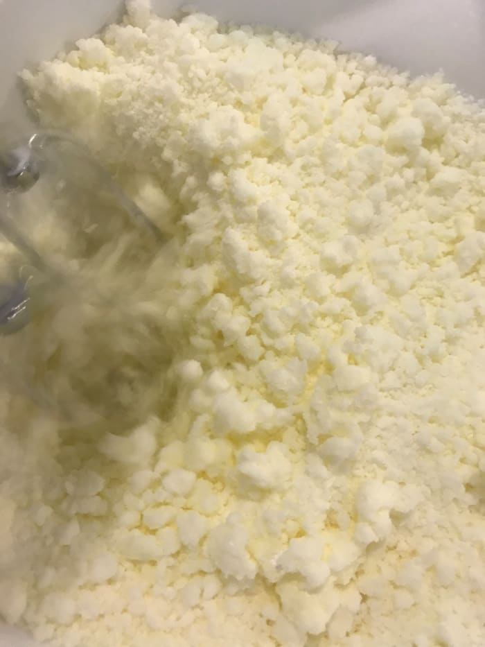 Beat together the butter and powdered sugar until the mixture is light and fluffy. It will almost resemble coarse sand, and you shouldn't see any obvious lumps of butter. Beating well at this stage helps ensure the finished frosting is super smooth.