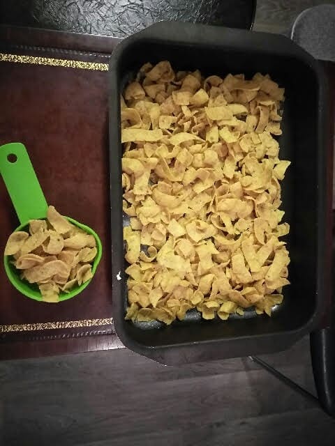 One cup of Fritos is reserved for the topping (left) and the rest of the Fritos line the bottom of the baking pan (right).