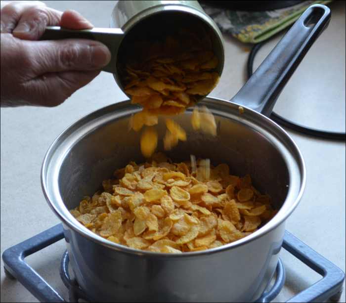 Corn Flakes being added to frothing ingredients to make the Honey Joy Biscuits.