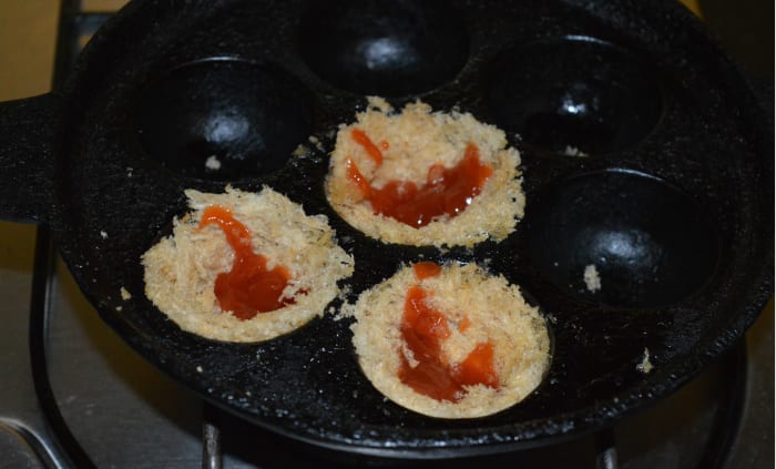 Step four: Place each slice with the butter portion touching the pan. Gently press it on all sides to give it a cup shape. Add some pizza sauce into all the cups.
