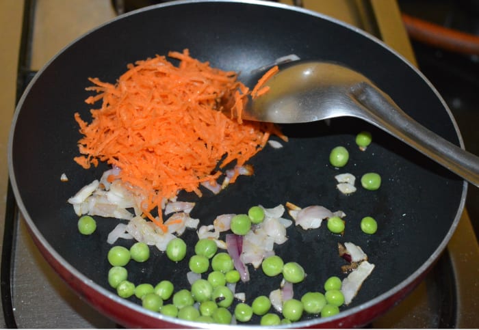 Step one: Saute onions in some oil until they get transparent. Next, Add grated carrots, chopped green chilies, green peas, and salt. Continue sauteing for four minutes.