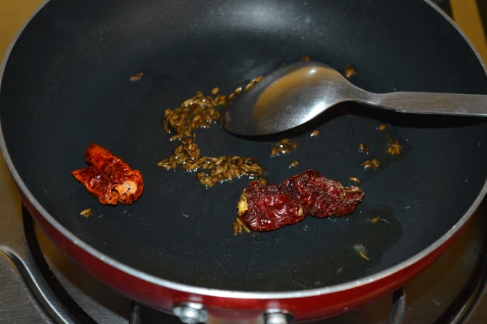 Step one: Heat half a teaspoon ghee or oil in a deep-bottomed pan. Throw in cumin seeds and red chilies. Saute till cumin seeds sizzle.