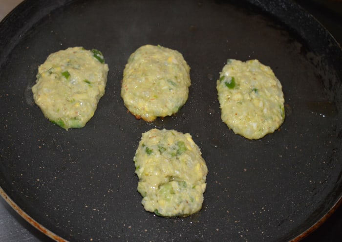 Step three: Take some dough in your fingers and form patties. Place 4 or 6 of them on a greased hot pan. Add a few drops of oil on the top.