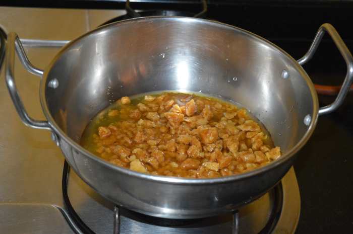 Step five: Add powdered jaggery to a thick-bottomed pan. Add 1/4 cup of water. Turn on the heat. Stir the mix for 5 to 6 minutes or until it becomes a bit thick and sticky.
