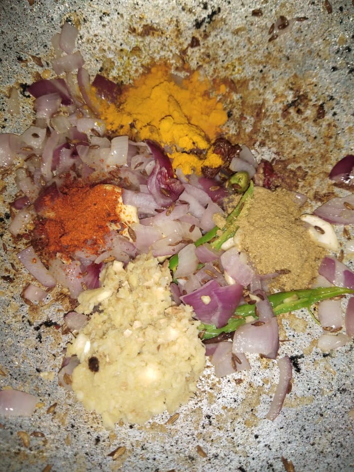 Add ginger-garlic paste and dry masalas (i.e., turmeric powder, red chili powder, coriander powder). Mix everything properly. Saute until the raw smell of the ginger-garlic goes away.