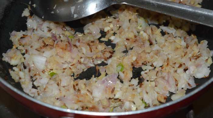 Step three: Saute cumin seeds in oil. Throw in the chopped onions. Saute until they become pinkish. Add ginger-garlic-green chili paste. Saute the mixture for 30 seconds.