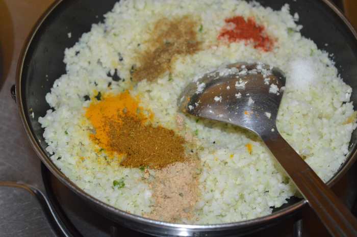 Step four: Add all the spices. Blend well. Cook, while sprinkling in a few drops of water. Cover the pan for faster cooking. Continue cooking until cauliflower gets cooked yet retains crunchiness. Turn off the heat.