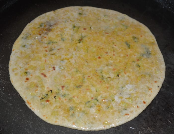 Step six: Cook the disc on a griddle. Press it all over for uniform cooking. Cook until you see golden brown spots on both the sides. Add a few drops of oil or ghee on both the sides. Remove and place on a plate.