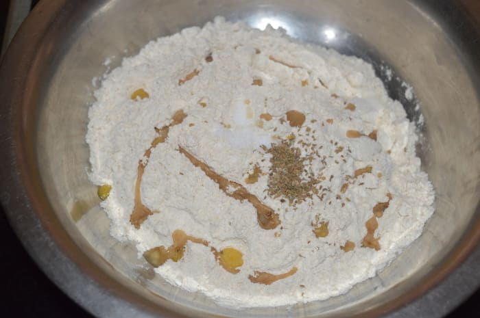 Step one: Add wheat flour, oil or ghee, salt, and carom seeds to a mixing bowl. Knead, adding water as needed to form a firm and pliable dough.