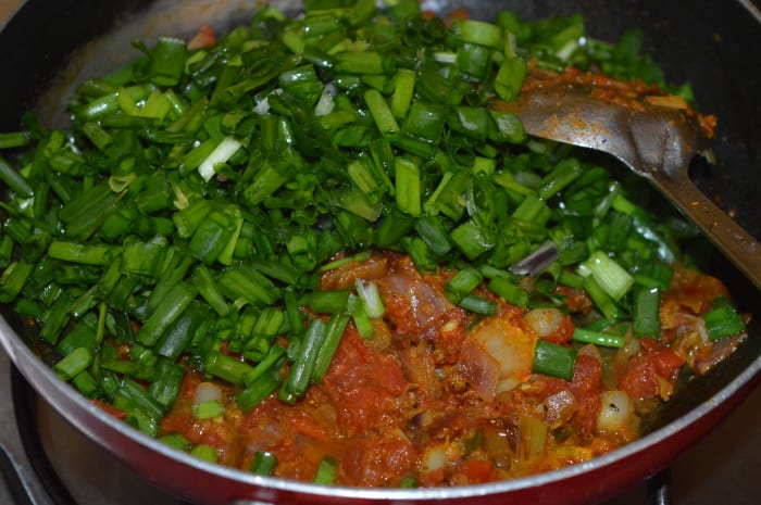 Step four: Add chopped spring onion greens. Mix well. Continue cooking until the spring onion greens wilt.