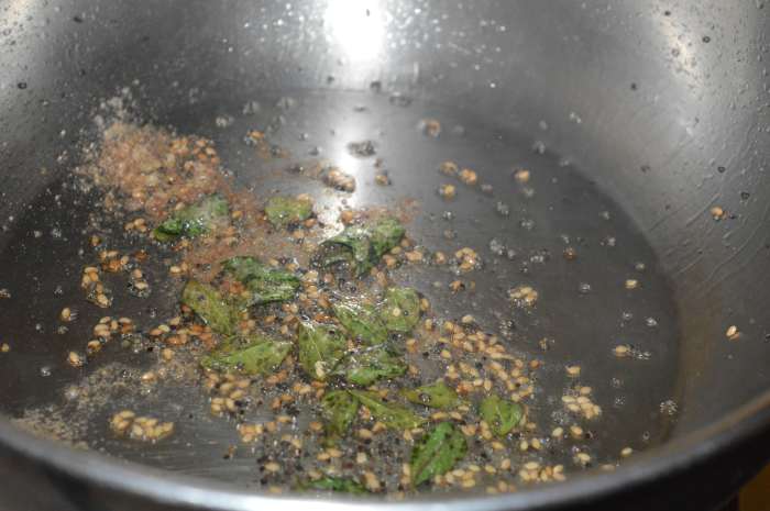 Step six: For making the seasoning, heat the oil in a large pan. Add mustard seeds, sesame seeds, curry leaves, and hing powder. Saute until mustard seeds pop. Turn off heat.
