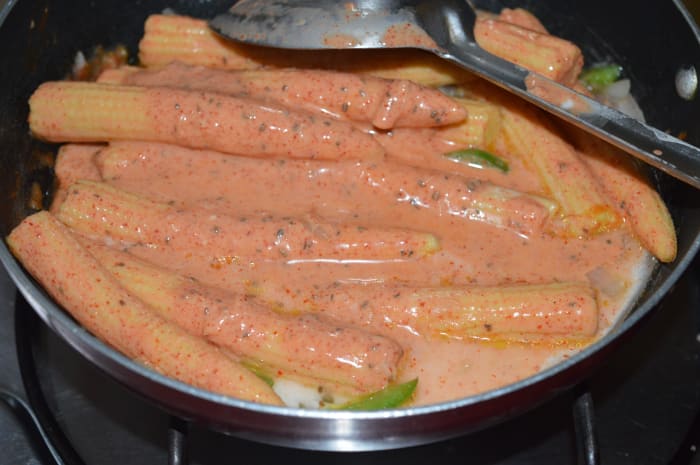 Step 4: Add the marinated baby corn and corn flour mixture. Gently mix with the other content in the pan. Turn off the heat when the baby corn gets coated with the spices and the raw smell of the corn flour disappears.
