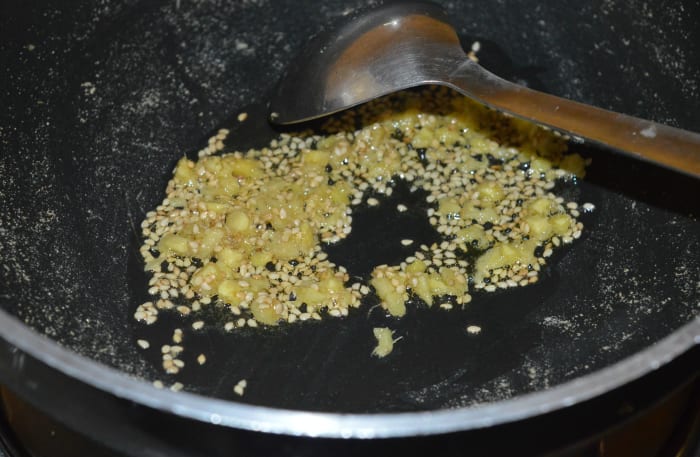Step three: Heat oil in a deep-bottomed pan. Add nigella seeds or sesame seeds and chopped ginger. Saute until the seeds are roasted. Turn off the heat.