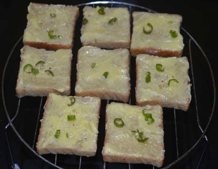 Sprinkle a little bit of salt on all the slices. Add chopped chilies and chopped garlic evenly on the top of all the buttered slices.