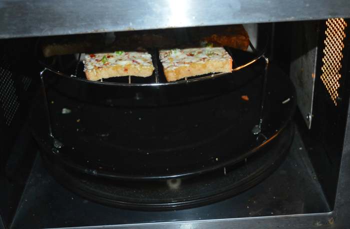 Place the grill stand in the preheated oven. Grill it for 1 minute. Open the oven and check whether the cheese has melted. If not, grill it for some more time, until the cheese melts properly.