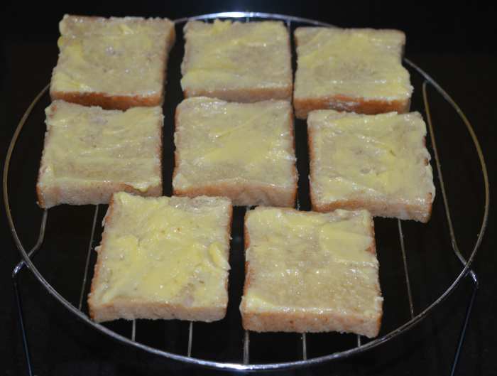 Step two: Take the grill stand out. Apply butter on the top side of all the slices. Arrange them on the grill stand.