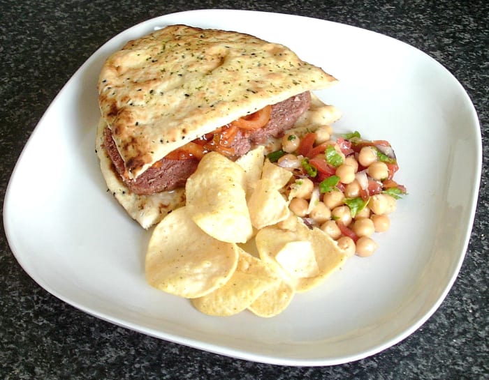 Corned beef and spiced onions naan bread sandwich is served with spicy chickpeas salad and mini poppadoms