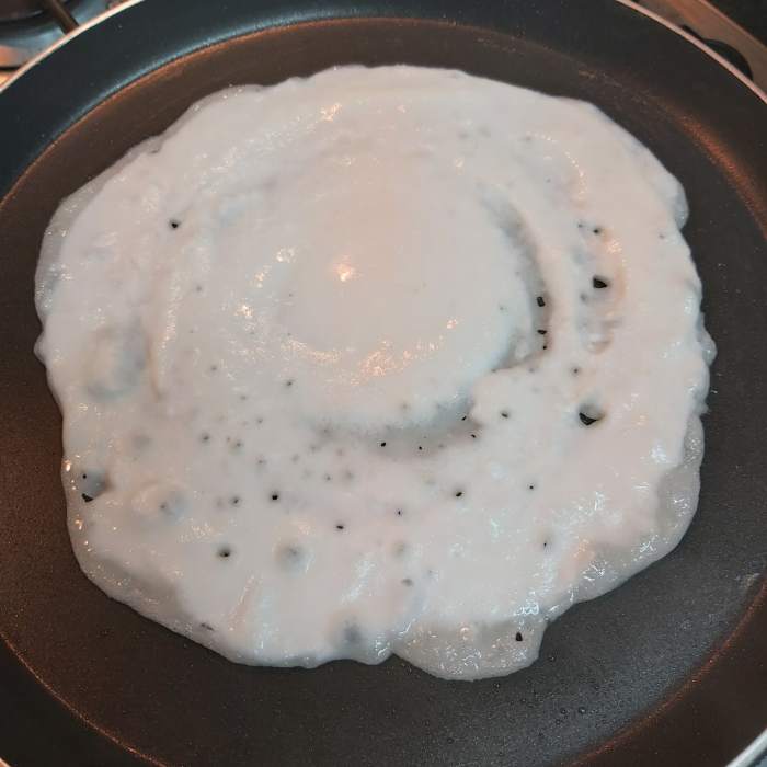 Heat a dosa tawa very well. Smear 1/2 teaspoon of oil and pour the prepared batter over the hot tawa. Do not spread the batter too much. Just pour the batter and spread a little. You don't need to get a perfect circle.