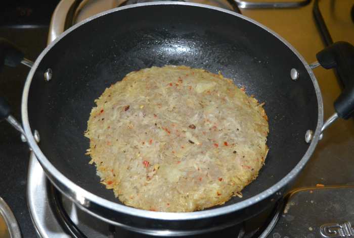 After 15 minutes, check whether the edges have become crispy and brownish. Also, the surface should appear dry. If not, increase the flame a little bit and cook until the edges become brownish. Once done, flip it over.