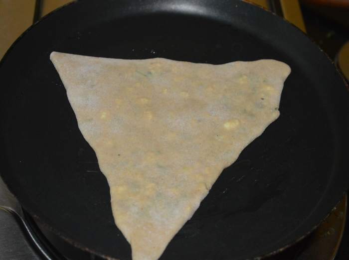 Cook the paratha until the bottom side gets golden brown spots. Flip it. Add a few drops of oil on the top side. Cook the other side too until it gets golden brown spots.