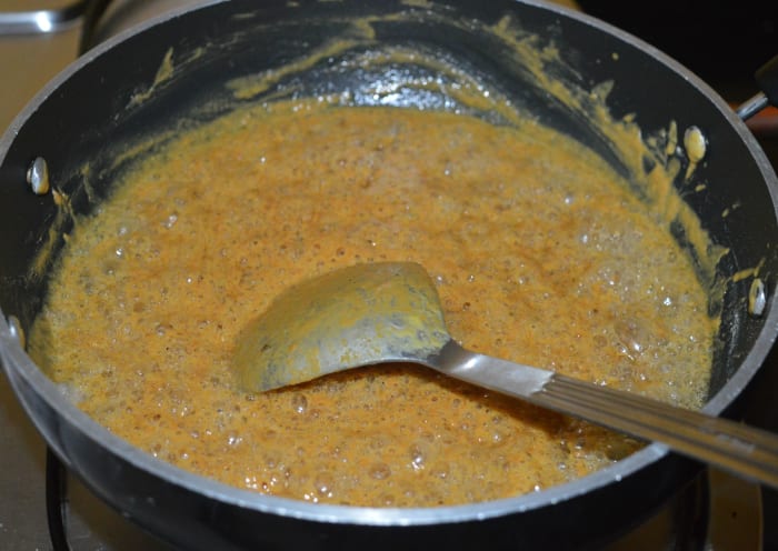 Step three: Add the sugar syrup to the pan containing besan mixture. Heat the pan. Stir the mixture for a minute. Turn off heat.